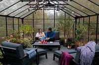 Father and daughter relaxing in lounge furniture in greenhouse in late November