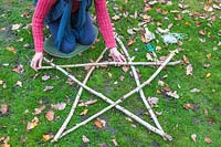 Woman placing the equal length hazel sticks into a star shape