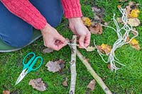 Woman using lengths of twine to tie together the ends of Hazel sticks to form the star shape