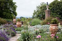 Summer border with ornate terracotta urns and beds planted with Lavandula angustifolia and Stachys byzantina