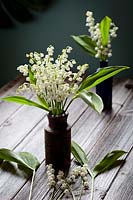 Rustic table setting featuring a posy of lily of the valley - Convallaria majalis in a clay jar