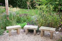 Rustic wooden seats alongside oregano, grasses and fennel  - Sedlescombe Primary School, Sussex, UK. 