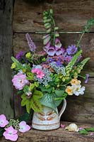 Mixed cut flowers in a jug: Digitalis - Foxglove, Heucherella, Geranium, Rosa, Brunnera, Rosa 'Goldfinch' and Cow Parsley