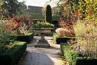 View along path to central urn with four beds edged with Euonymus 'Green Spire' containing Rosa and Cotinus