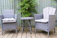 Deck with armchairs and small table in same colour as painted fence