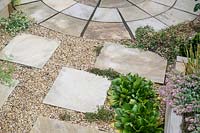 Stepping stone path in gravel with planting, leading to circular paving 
