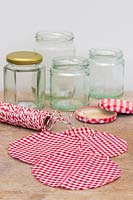 Collection of empty glass jars and lids, including material toppers and string. 