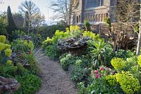 Pathway through colourful spring planting in the Stumpery Garden, with Helleborus foetidus, Euphorbia, tulips, fritillaries and Pulmonaria. Arundel Castle, West Sussex, UK.
