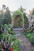 The Stumpery garden with decorative sculptural logs, a living sculpture seat and Muscari, fritillary, ferns and hellebores. Arundel Castle, West Sussex, UK.
