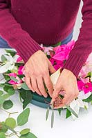 Woman adding Eucalyptus sprigs to cover the sides of the wreath