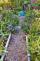 Raised beds planted with mixed herbs and vegetables in enclosed kitchen garden.
