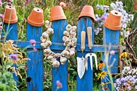 Plaited Garlic and tools hanging on a fence