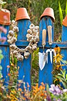 Plaited Garlic and tools on a fence