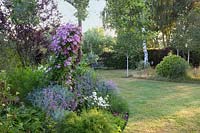 Pretty pastel themed summer border alongside lawn 