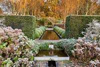 View towards the Upper Rill Garden on a frosty December morning. Planting includes: clipped yew hedge 'Taxus baccata', Hydrangea macrophylla, fastigate hornbeam, Carpinus 'Frans Fontaine', and box balls.