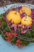 Moss wreath filled with small squash, berries, leaves and crab apples