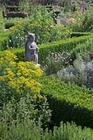 Stone angel statue in herb garden with box hedges with Rue, Santolina, Rosemary and Chives -  Holland