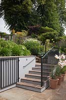Steps and railings in cottage garden on a slope with flowerbeds, Cheshire