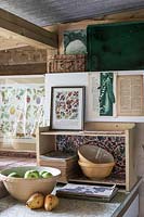 Old fashioned vintage kitchen area for vegetable preparation in garden room, filled with gardening paraphanalia and wall art