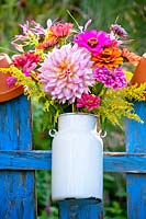 Flower bouquet in a milk can on a fence