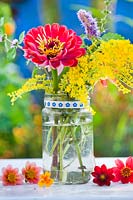 Flower arrangement of Zinnia and Solidago in a glass jar