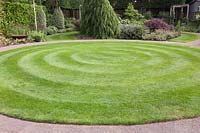 Curving gravel path around circular lawn. 
