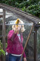 Cleaning greenhouse glass with a brush before winter