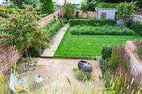 An overview of a contemporary city garden with gravelled seating area, raised lawn and wildflower border