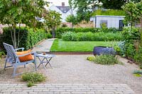 A contemporary city garden with gravelled seating area, raised lawn, wildflower border and green-roofed garden room.