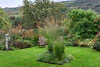 Square bed in lawn planted with Molinia caerulea, purple moor grass