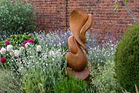 Wooden sculpture by Peter Leadbeater, chainsaw sculptor in summer border 