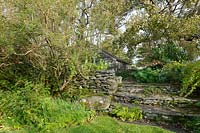 A dry stone wall and stone steps leading to a stone building 
