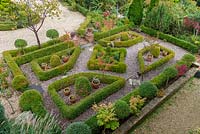 Bird's eye view of a formal parterre created from clipped box hedges, balls and standard, infilled with gravel and herbs.