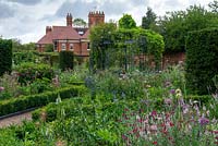 A Victorian walled garden with a central arbour and beds around with planting of Roses, Alliums, Mallows, Foxgloves, Lychnis, Sea hollies, Toadflaxes and Laceflowers