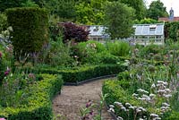 A parterre planted with Roses, Alliums, Lychnis, Phloxes, Toadflaxes and Mallows