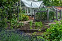 A formal kitchen garden with bespoke oak cloches to protect vulnerable crops, raised beds for runner beans and carrots, and a greenhouse.