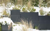 Grasses in metal containers covered with snow.