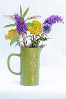 Green jug with Buddleia 'Davidii,' Nanho Blue', Echinop, Achillea millefolium, Hebe 'Amy'