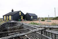 Cottage and garden on a shingle beach, old boat hull in foreground