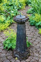 Sundail at centre of circular paved patio with Alchemilla mollis 