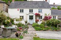 A front garden with seating and Rosa - Climbing Rose - around cottage