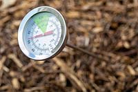 Thermometer or temperature gauge inserted into compost
