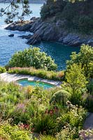 Looking down on flower beds around swimming pool, set on cliff with sea below