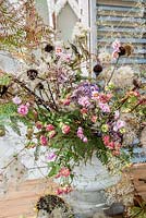 Autumnal floral arrangement in urn with dried and foraged florals inc echinacea, Clematis, bracken, hydrangeas, echinops