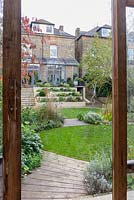 Low maintenance  city garden - stepped beds and stairs seen through greenhouse door