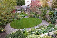Low maintenance city garden overview of oval lawn with decking edging