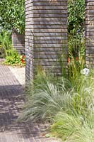 Garden with ornamental grasses divided by belgium brick paver columns and walls. RHS Sanctuary Garden - Hampton Court Flower Festival 2019 