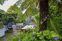 Family Small Hackney Garden  - dining area with Geranium and tree fern by Earth Designs
