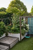 Swing and raised bed with planting with Allium, white Hydrangea and Erigeronby Earth Designs