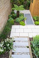 View of paved pathway in London garden, with raised stepping stones and gravel infill. By Earth Designs
